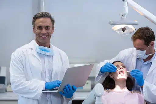 Dentist using a laptop during a patient appointment, representing social media marketing on Facebook for dental growth