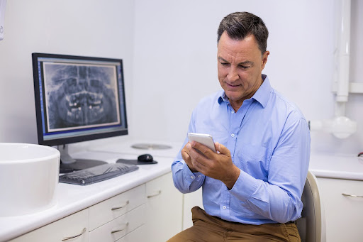 Orthodontist checking a mobile device in the clinic, representing an orthodontist marketing company