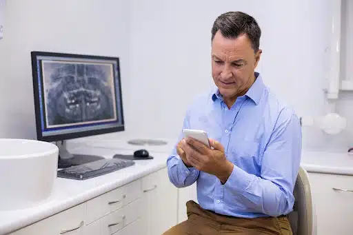 Orthodontist checking a mobile device in the clinic, representing an orthodontist marketing company