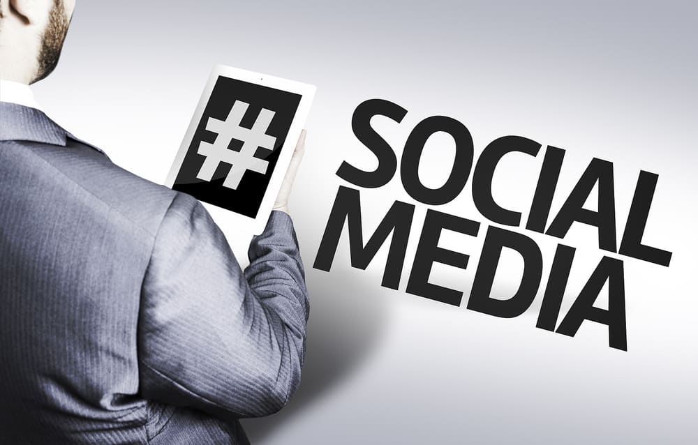 Business professional holding a tablet with hashtag symbol representing dental social media marketing ideas