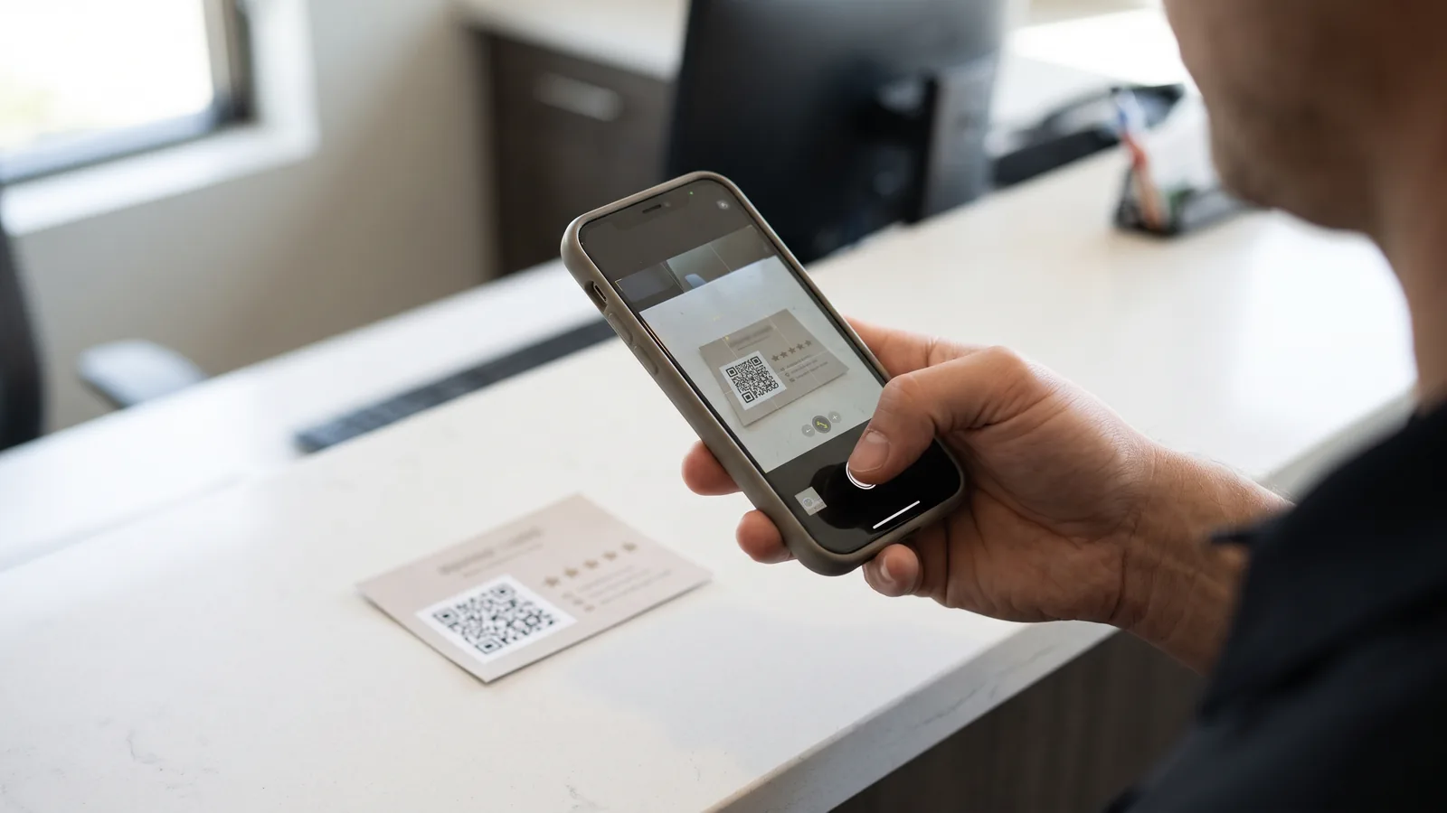 A person scans a review request QR card at a dental reception counter.